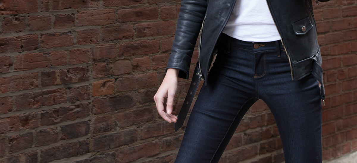 Woman in dark denim leaning on a railing, leather jacket, NYC street
